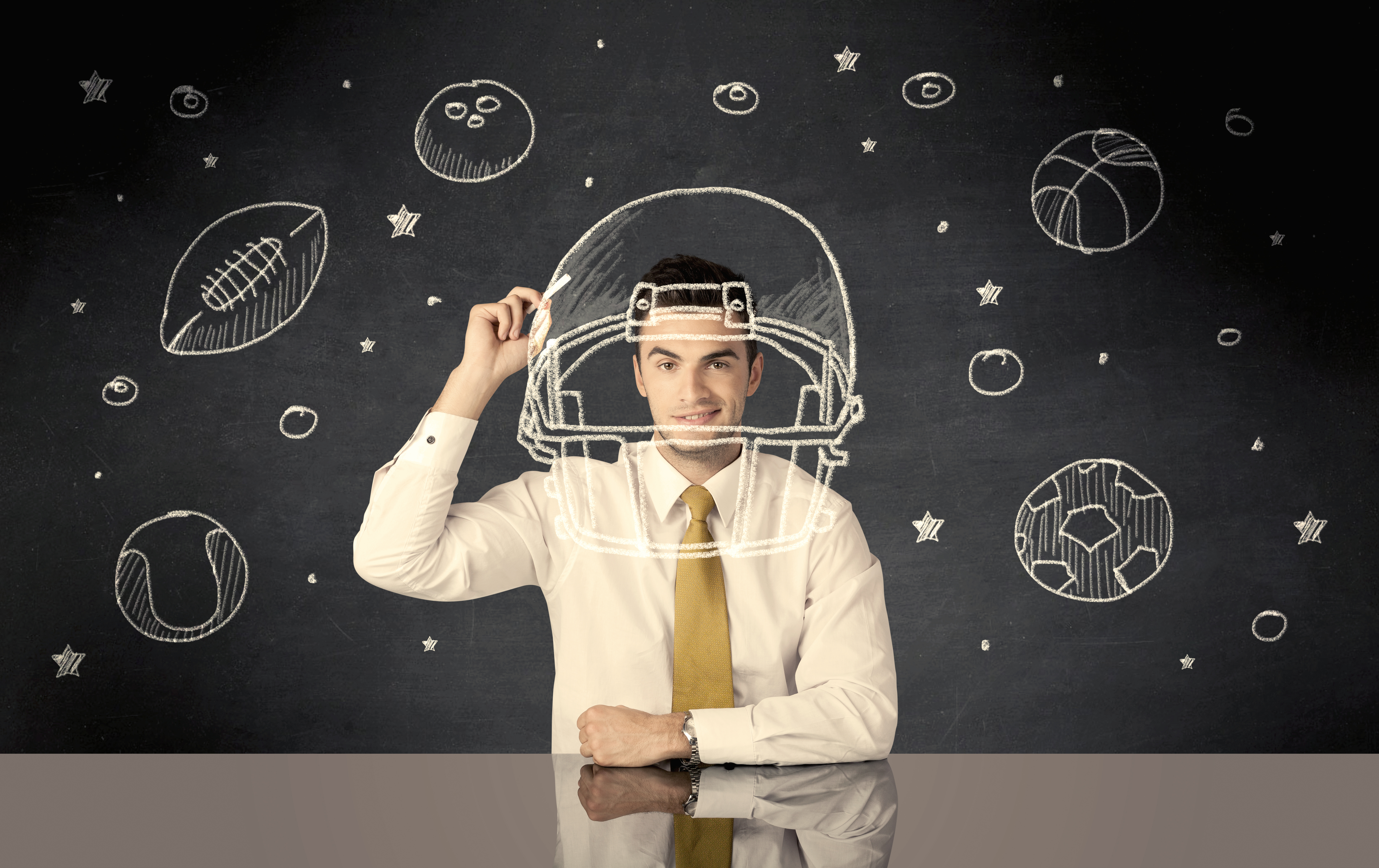 A happy college graduate dreaming about becoming a successful sports person while drawing helmet and ball in space concept