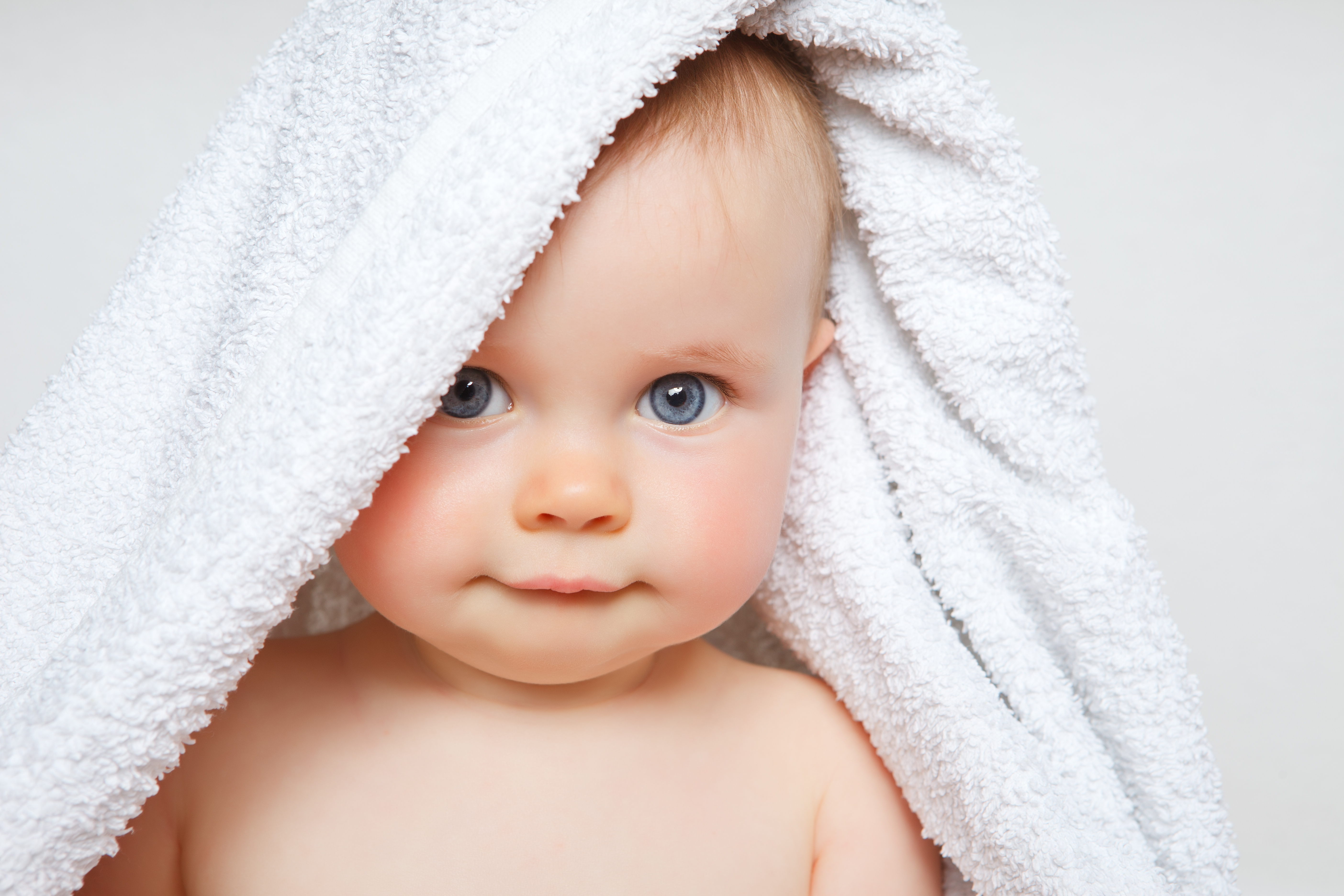 little baby smiling under a white towel