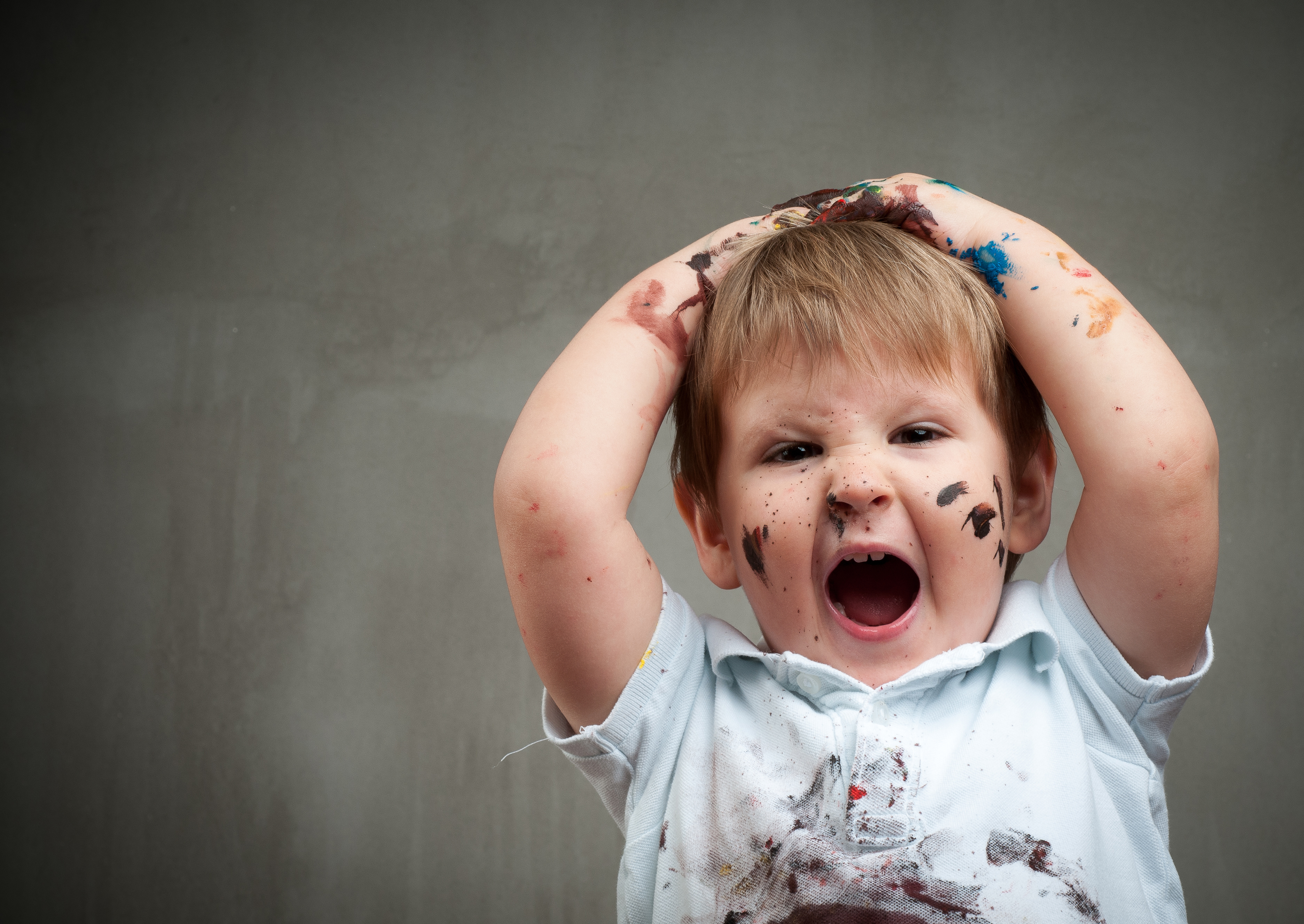 Little boy playing with bright colors, getting messy hands and face