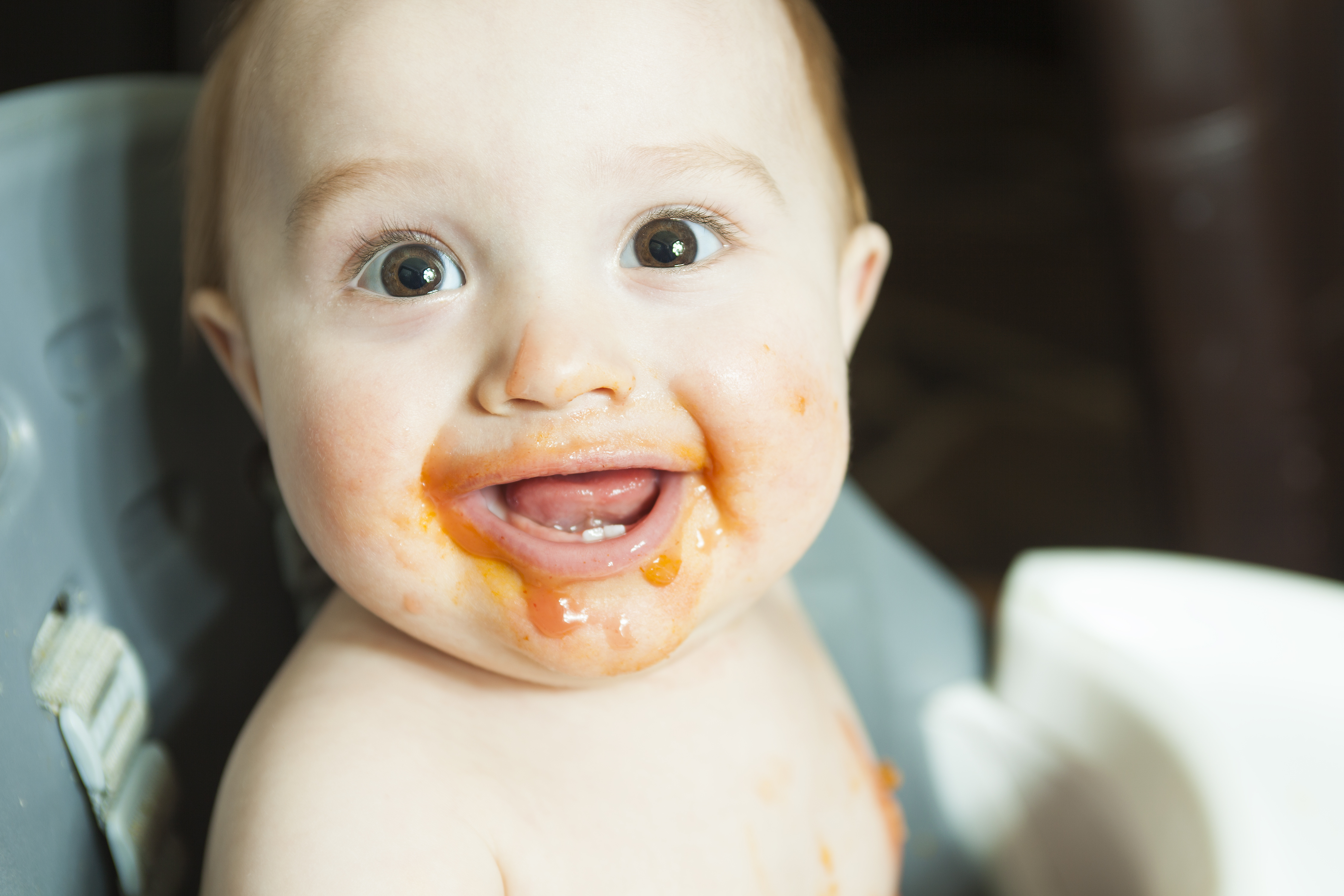 A Mother feeding hungry six month old baby solid food
